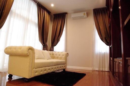 Spacious and elegant living room with large windows, draped curtains, and a comfortable couch