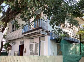 Exterior view of a two-story residential building with trees and a fence