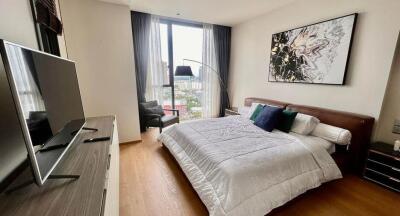 Modern bedroom with a large window, bed, TV, and artwork on the wall