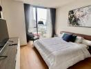 Modern bedroom with a large window, bed, TV, and artwork on the wall