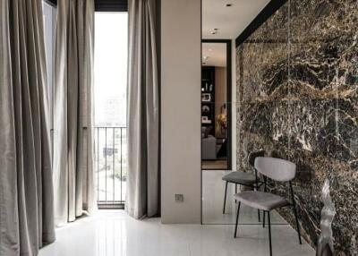 Modern living area with floor-to-ceiling windows, marble accent wall, and contemporary chairs