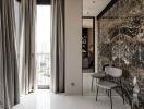 Modern living area with floor-to-ceiling windows, marble accent wall, and contemporary chairs