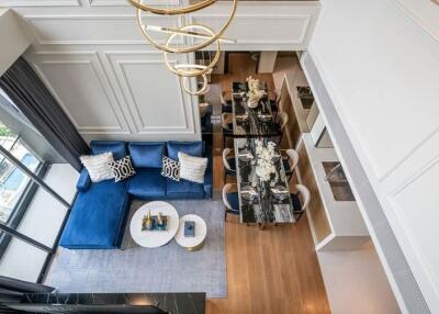 Spacious living room with a view, featuring a blue couch, modern dining area, and high ceiling.