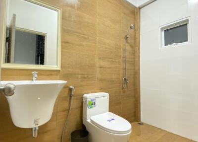 Modern bathroom with wooden accents, featuring a basin, toilet, shower area, and small window