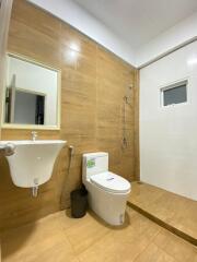 Modern bathroom with wooden accents, featuring a basin, toilet, shower area, and small window