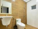 Modern bathroom with wooden accents, featuring a basin, toilet, shower area, and small window