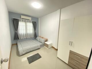 Spacious and well-lit bedroom with a bed, wardrobe, and window with curtains