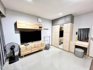 Modern bedroom with storage, TV, and a vanity area