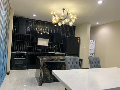 Modern kitchen with black backsplash, island, and dining area.