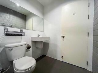 Modern bathroom with toilet, sink, and large mirror