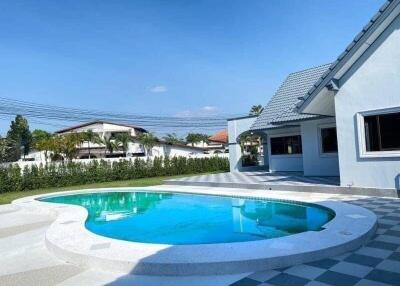 Outdoor swimming pool with surrounding patio and adjacent house