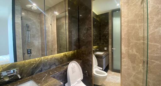 Modern bathroom with glass shower, marble walls, and a toilet
