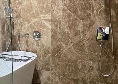 Modern bathroom with brown marble walls, bathtub, and shower