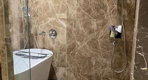 Modern bathroom with brown marble walls, bathtub, and shower