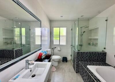 Modern bathroom with glass-enclosed shower, bathtub, and large mirror