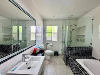 Modern bathroom with glass-enclosed shower, bathtub, and large mirror