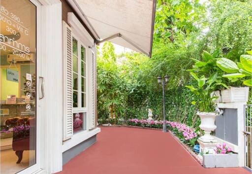 Beautifully landscaped outdoor patio area with a red floor, lush greenery, and decorative elements.