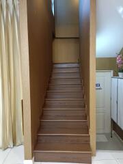 Staircase with wooden steps leading to the upper floor, adjacent to a white door and curtain