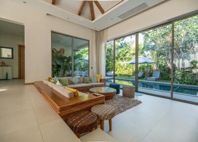 Spacious living room with modern decor and large glass doors leading to a lush garden and pool
