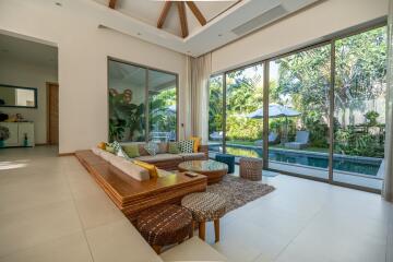 Spacious living room with modern decor and large glass doors leading to a lush garden and pool