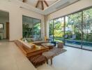 Spacious living room with modern decor and large glass doors leading to a lush garden and pool