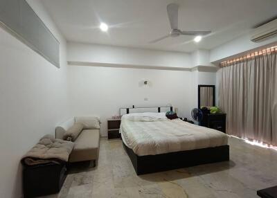 Spacious bedroom with bed, couch, air conditioning, and ceiling fan