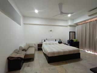 Spacious bedroom with bed, couch, air conditioning, and ceiling fan