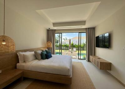 Spacious bedroom with modern furnishings and a view of the outdoor area through large sliding glass doors.