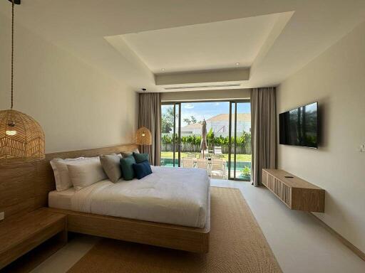 Spacious bedroom with modern furnishings and a view of the outdoor area through large sliding glass doors.