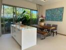 Modern dining area with a white island, wooden table, and large windows