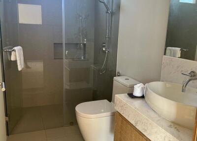 Modern bathroom with glass shower, toilet, and sink