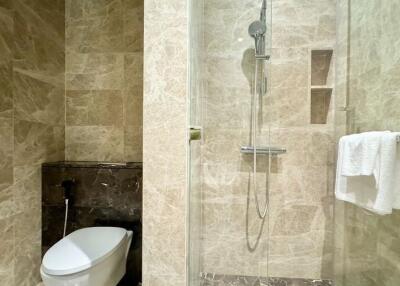 Modern bathroom with marble finish, glass shower door, and toilet