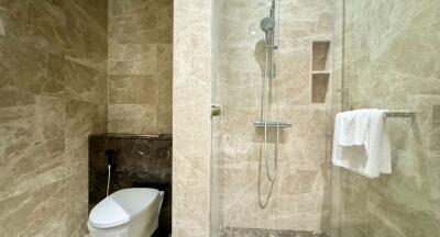 Modern bathroom with marble finish, glass shower door, and toilet