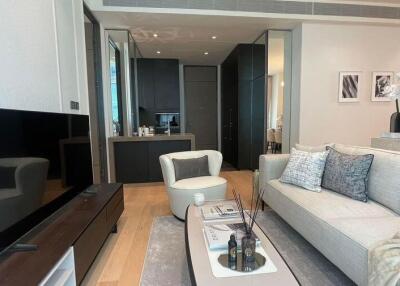 Spacious modern living room with a large couch, flat-screen TV, and open-plan kitchen in view
