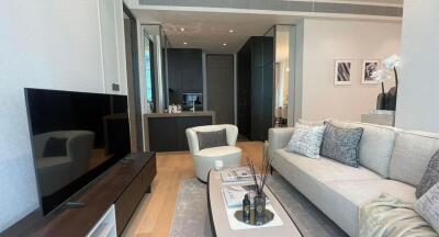 Spacious modern living room with a large couch, flat-screen TV, and open-plan kitchen in view