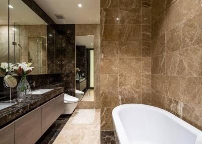 Luxurious marble-tiled bathroom with double sink and bathtub