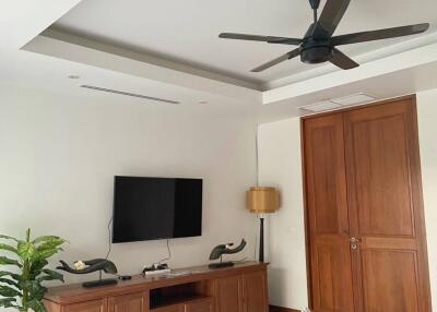 Modern living room with wooden furniture, TV, and ceiling fan