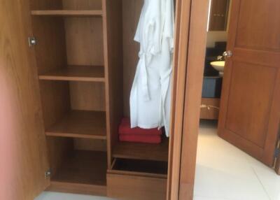 Open wardrobe with shelves and hanging bathrobes in a bedroom