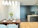 Modern dining area with table set for four and adjoining sleek kitchen