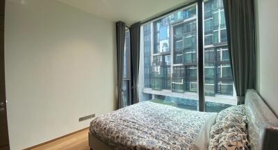 Bedroom with a view of neighboring building through large windows.