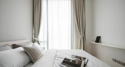 Modern bedroom with white bedding and a large window with curtains