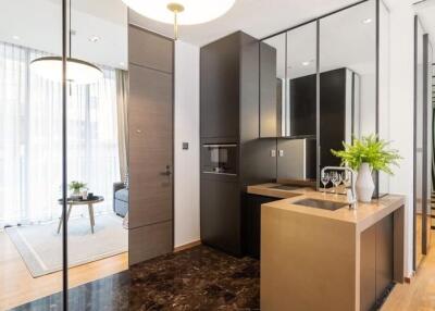 Modern kitchen area with sleek cabinetry and a small island adjacent to an open living space