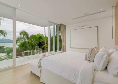 Spacious bedroom with large windows, balcony, and scenic view