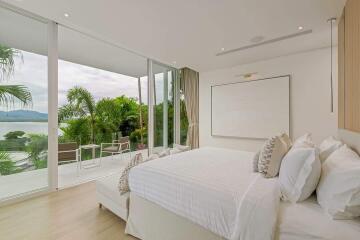 Spacious bedroom with large windows, balcony, and scenic view