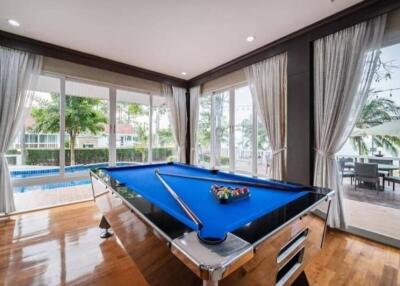 Room with large windows, pool table, and view of a pool and patio