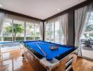 Room with large windows, pool table, and view of a pool and patio