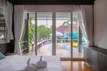 Bedroom with bed, large glass doors opening to a pool area with greenery