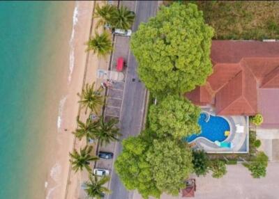 Aerial view of a beachfront property with a pool and surrounding greenery.