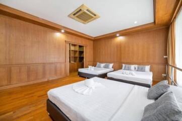 Spacious bedroom with three beds and wooden walls