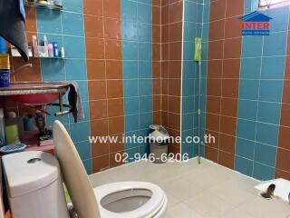 Bathroom with colorful tile walls, toilet, and various toiletries